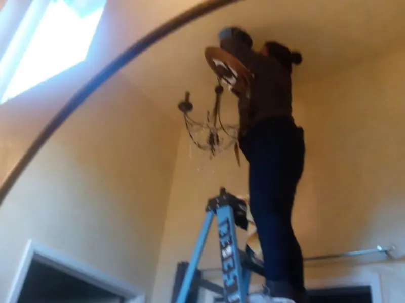 Electrician installing a chandelier in a Landover residence